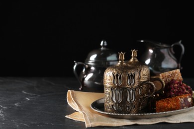 Photo of Tea and Turkish delight served in vintage tea set on dark grey textured table, space for text