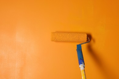 Photo of Painting wall with roller and orange dye