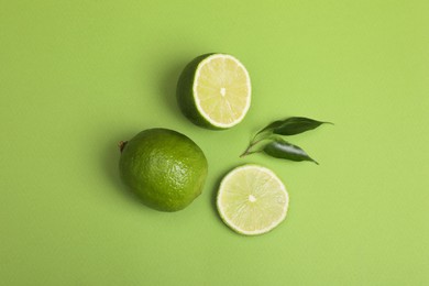 Photo of Fresh limes and leaves on light green background, flat lay