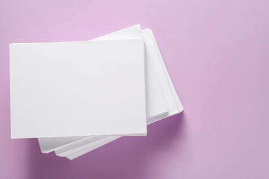 White paper sheets on violet background, top view. Space for text