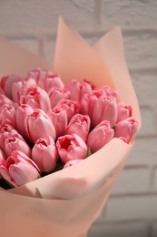 Photo of Bouquet of beautiful pink tulips near white brick wall, closeup