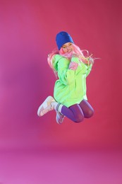 Photo of Cute indie girl jumping on violet background