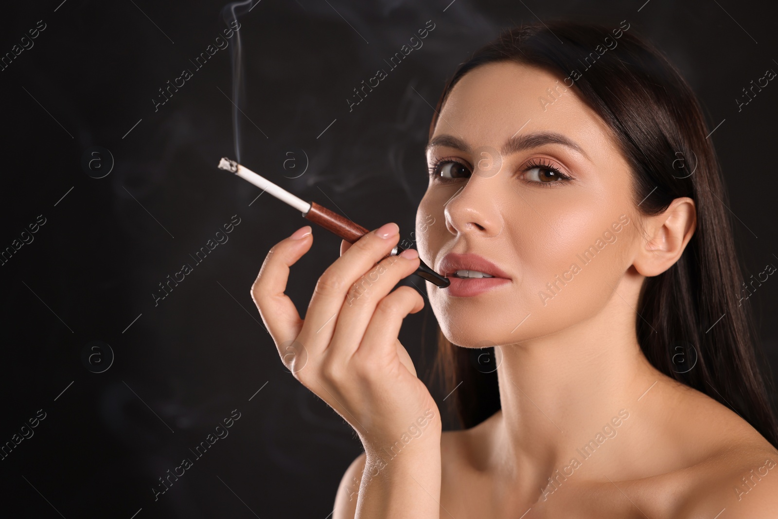 Photo of Woman using long cigarette holder for smoking on black background, space for text