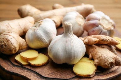 Photo of Ginger and fresh garlic on wooden board. Natural cold remedies