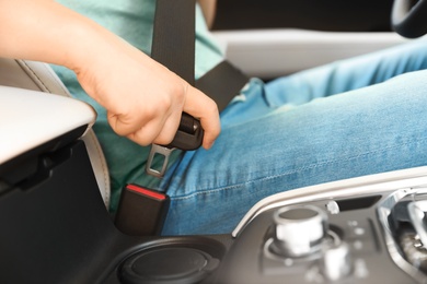 Male driver fastening safety belt in car, closeup