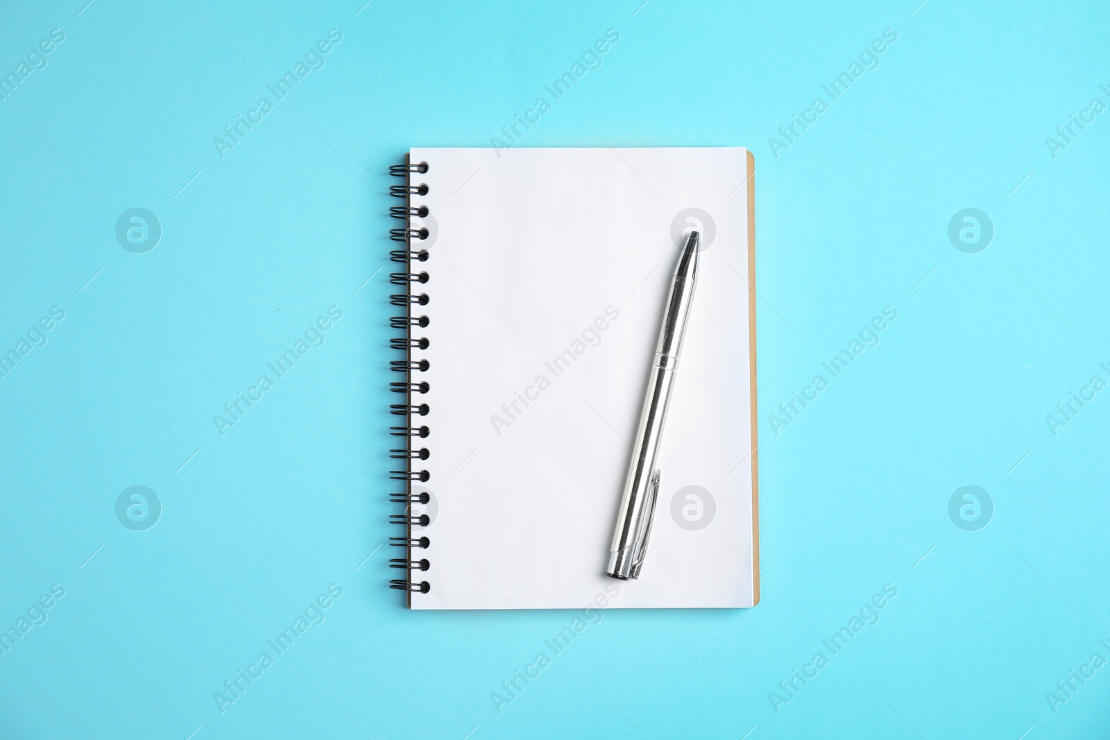 Photo of Empty notebook and pen on color background, top view