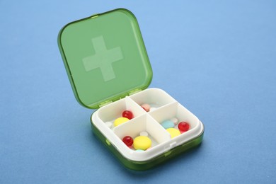 Plastic box with different pills on light blue background