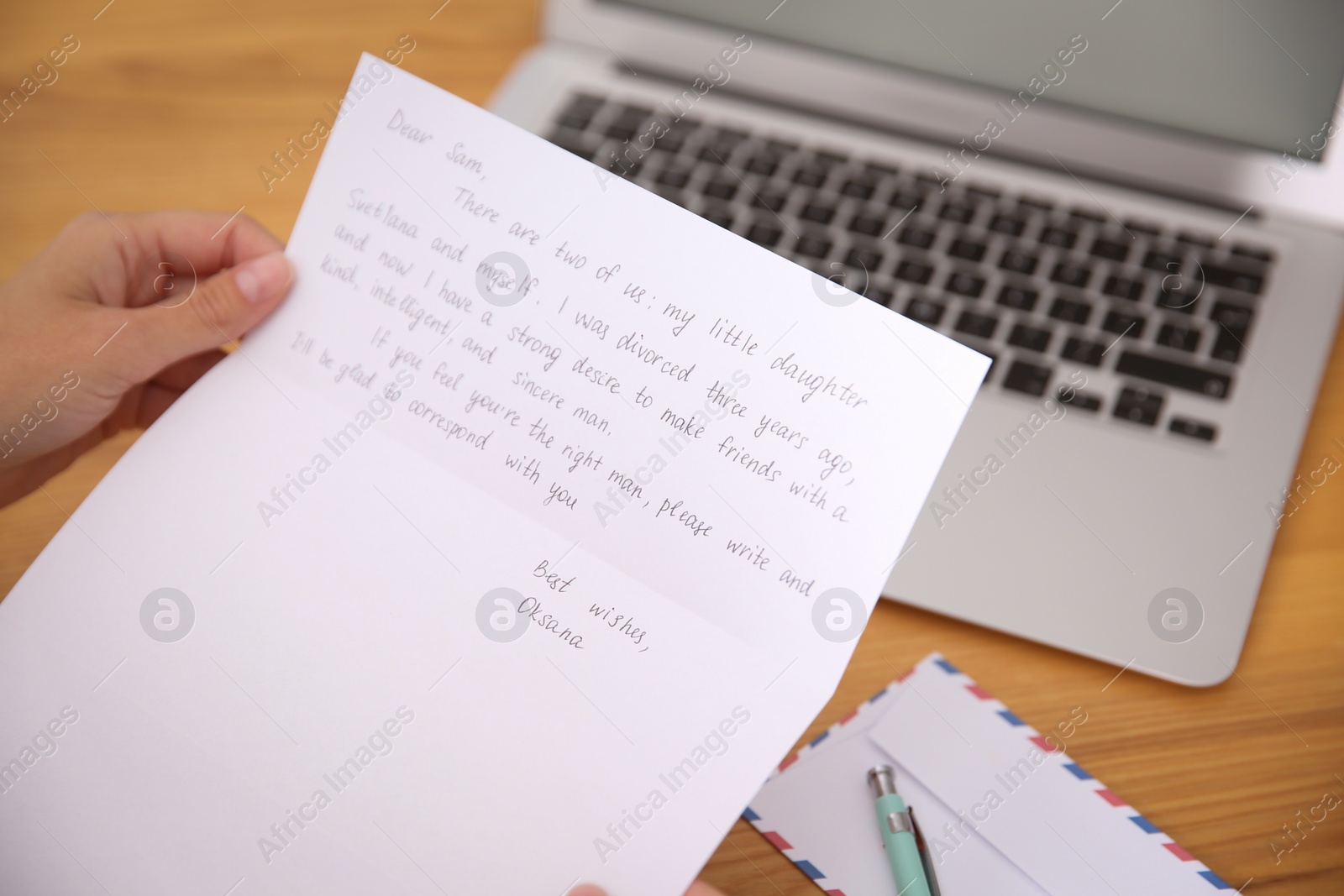 Photo of Woman reading letter at wooden table indoors, closeup