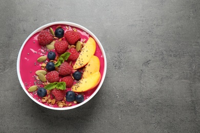 Delicious acai smoothie with granola and berries on grey table, top view. Space for text