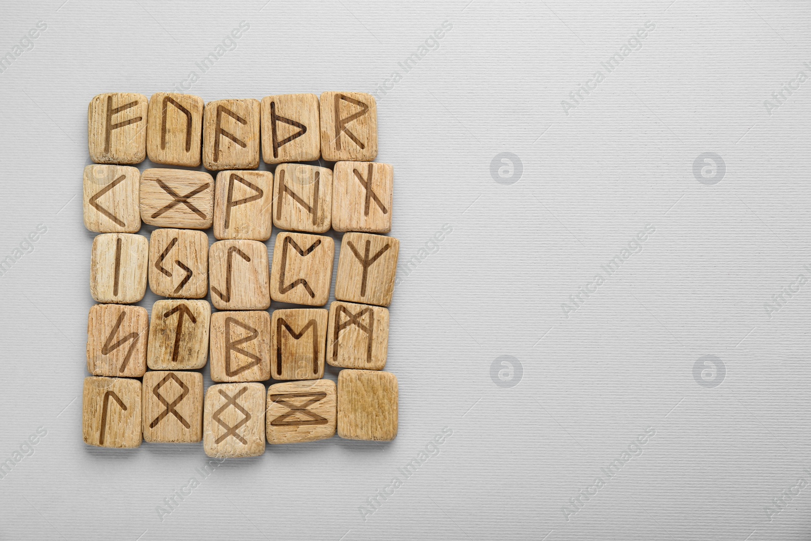 Photo of Wooden runes on white background, top view. Space for text