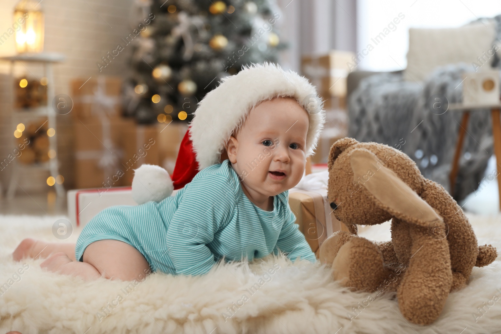 Image of Cute baby in Santa hat crawling on floor. First Christmas