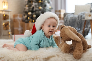 Image of Cute baby in Santa hat crawling on floor. First Christmas