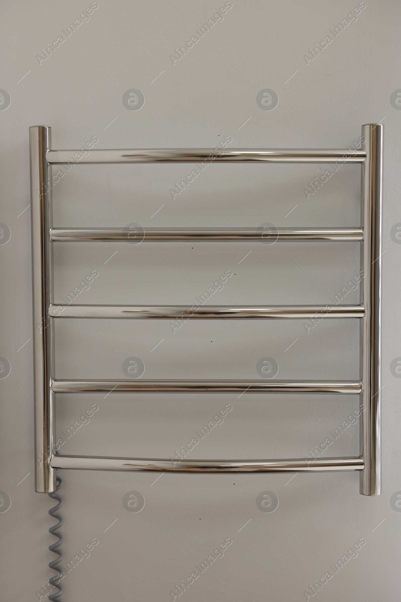 Photo of Heated towel rail on white wall in bathroom