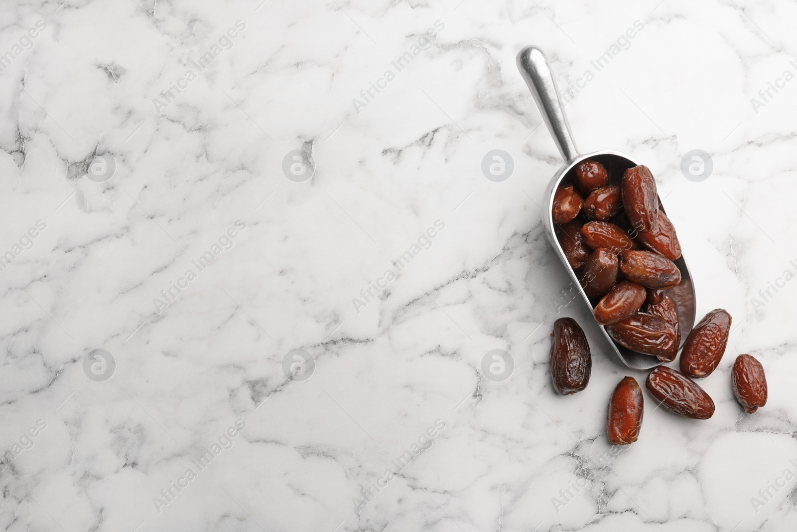 Photo of Scoop with sweet dried date fruits on marble background, top view. Space for text