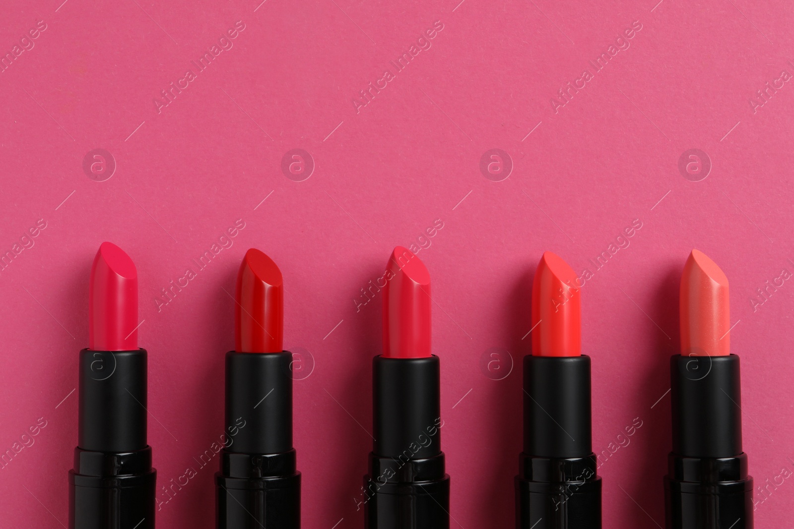 Photo of Beautiful lipsticks on pink background, flat lay. Space for text