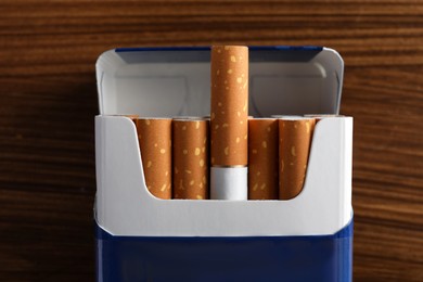 Photo of Pack of cigarettes on wooden table, top view