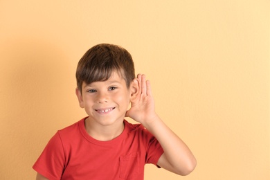Photo of Cute little boy with hearing problem on color background. Space for text