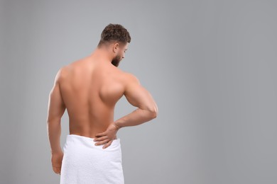 Photo of Man suffering from back pain on grey background, back view. Space for text