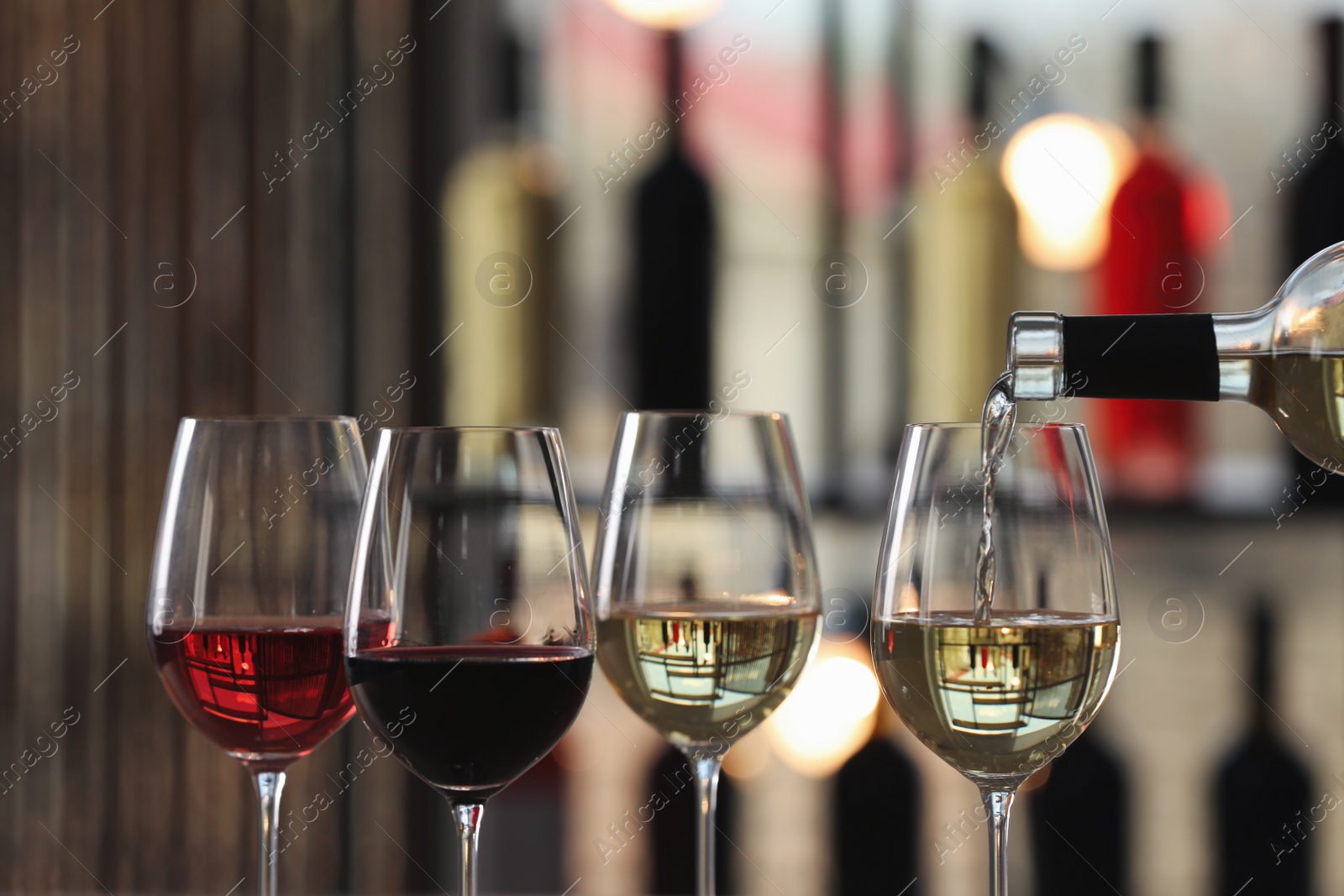 Photo of Pouring white wine from bottle into glass indoors, closeup