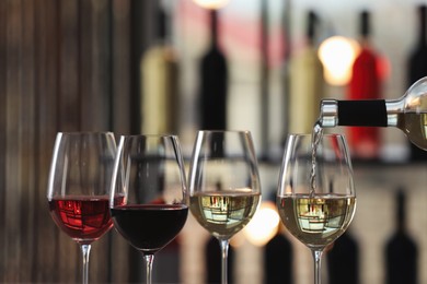 Pouring white wine from bottle into glass indoors, closeup