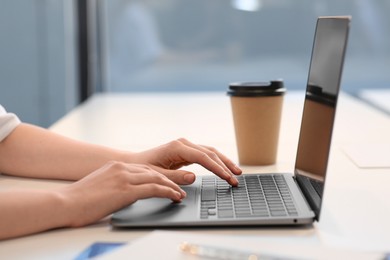 Photo of Woman working with laptop at white desk indoors, closeup