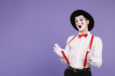 Photo of Mime artist making shocked face on purple background. Space for text