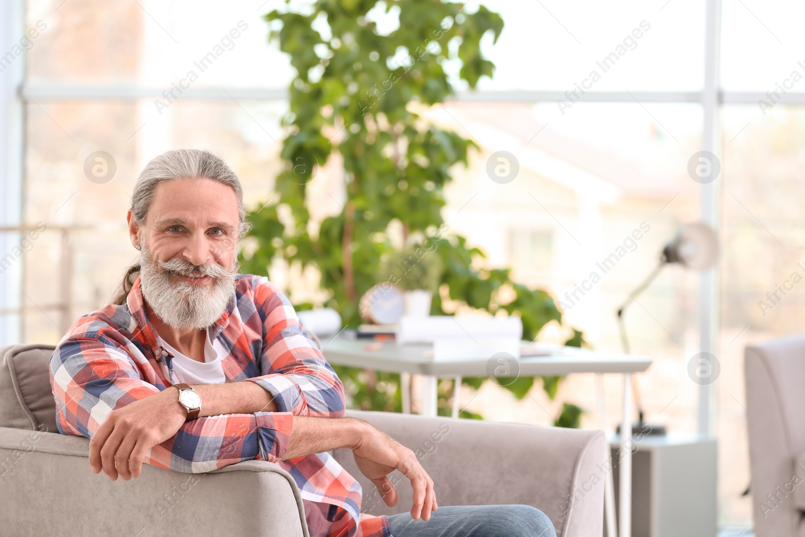 Photo of Handsome mature man sitting in armchair indoors