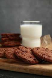 Board with tasty chocolate cookies and glass of milk on table, closeup. Space for text