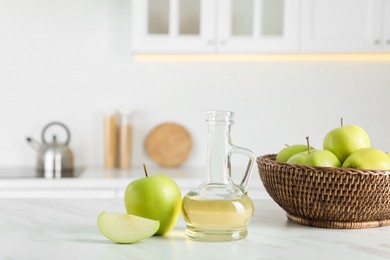 Photo of Natural apple vinegar and fresh fruits on white marble table in kitchen