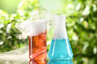 Photo of Laboratory glassware with colorful liquids on glass table outdoors. Chemical reaction
