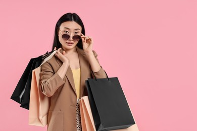 Photo of Beautiful woman with shopping bags on pink background. Space for text