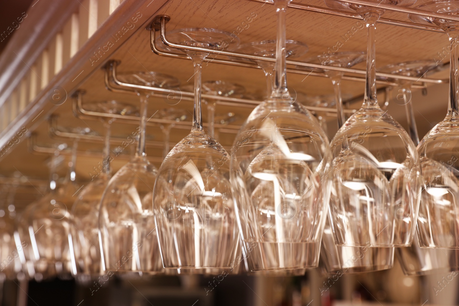 Photo of Set of empty clean glasses on bar racks