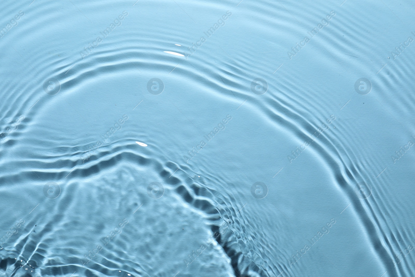 Photo of Rippled surface of clear water on light blue background, top view