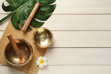 Flat lay composition with golden singing bowls on white wooden table. Space for text