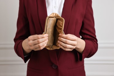 Photo of Woman with empty wallet near white wall, closeup