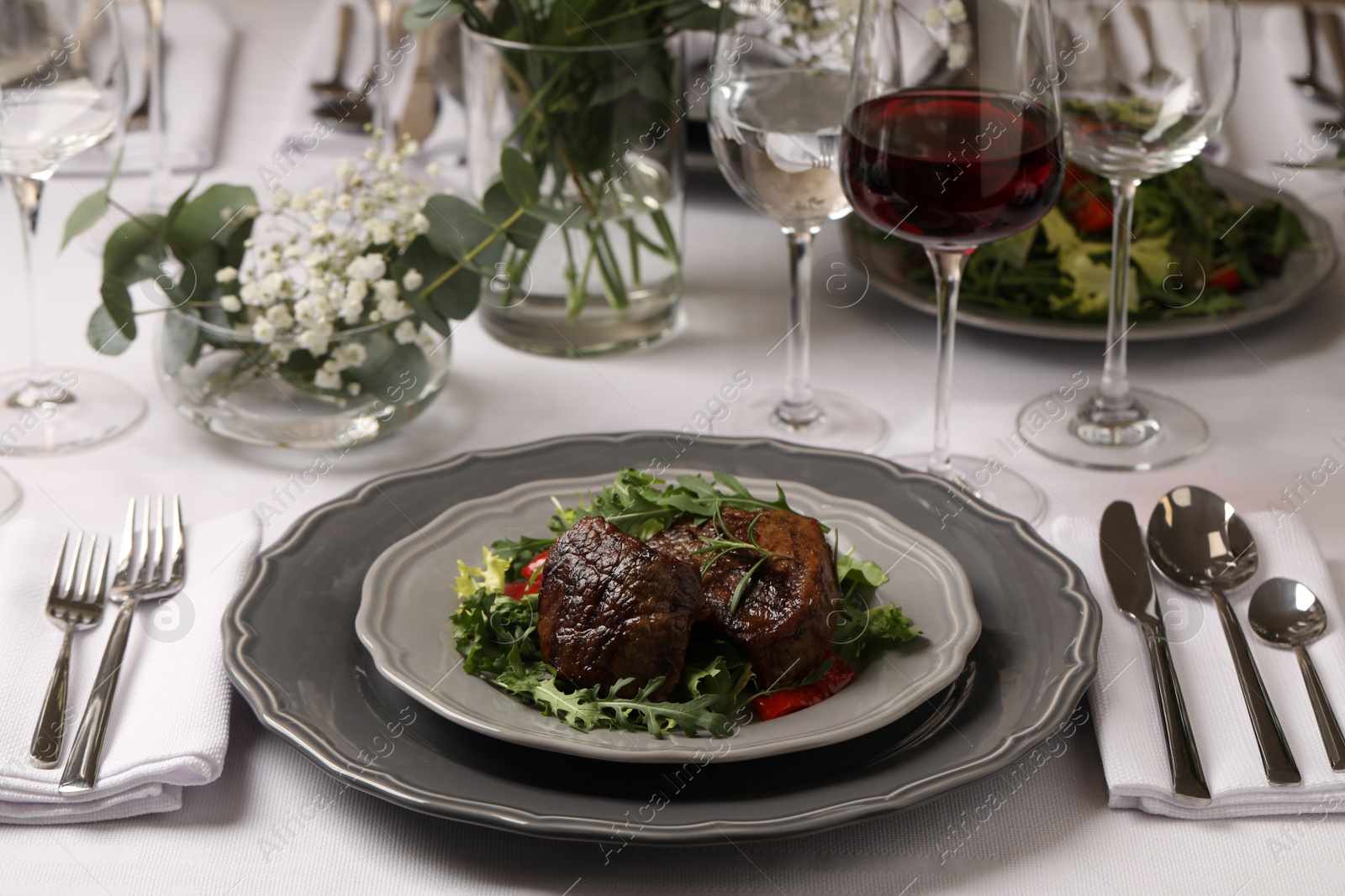 Photo of Delicious grilled meat with vegetables and wine served on table in restaurant