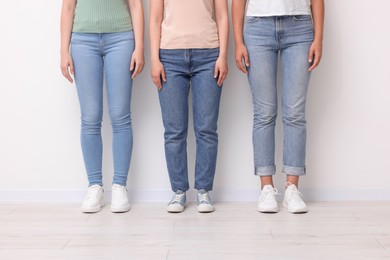 Photo of Women in stylish jeans near white wall, closeup