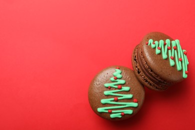 Photo of Beautifully decorated Christmas macarons on red background, flat lay. Space for text