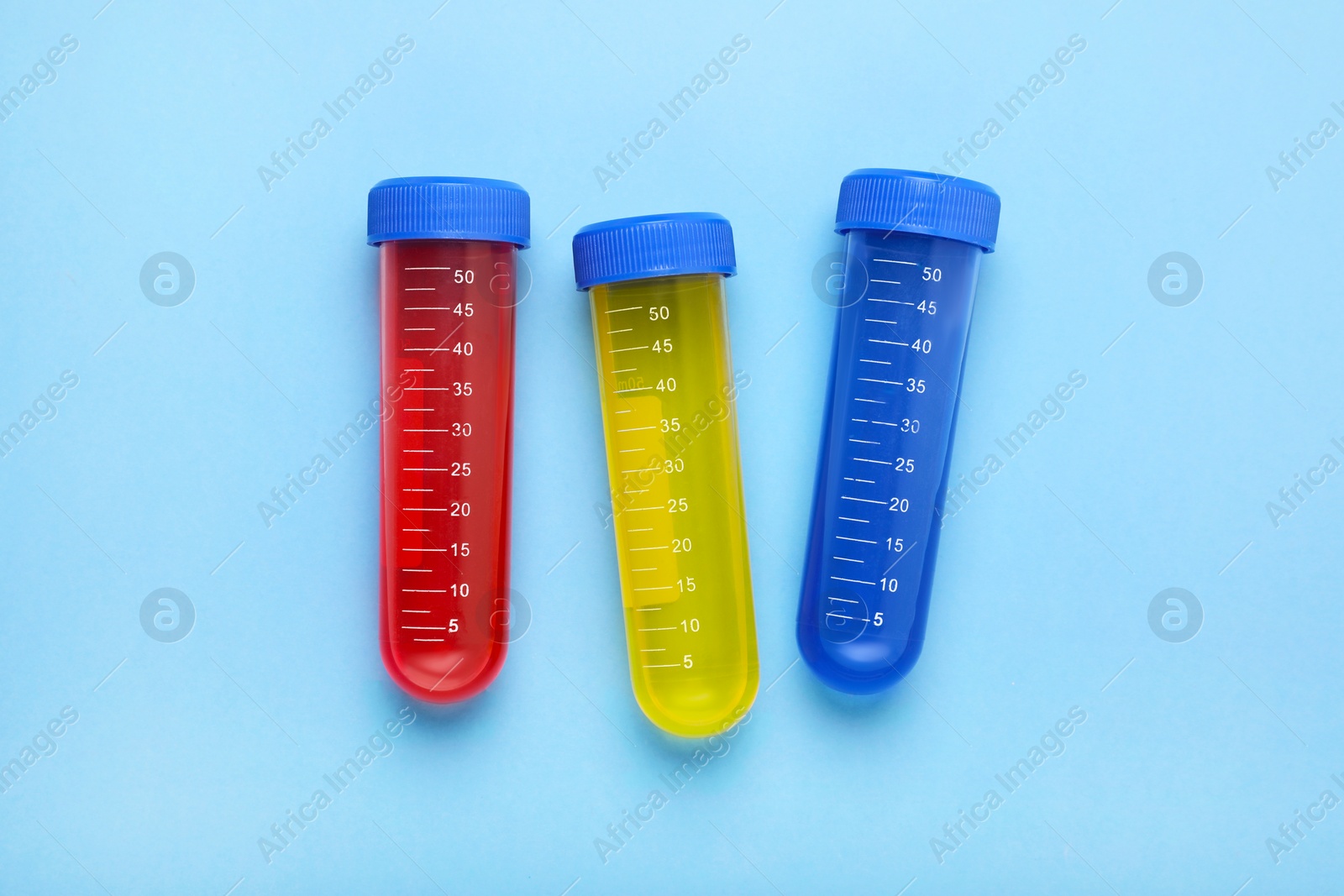 Photo of Test tubes with colorful liquids on light blue background, flat lay. Kids chemical experiment set