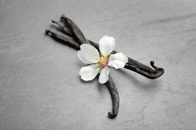 Photo of Aromatic vanilla sticks and flower on grey background