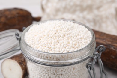 Photo of Tapioca pearls in jar and cassava roots, closeup