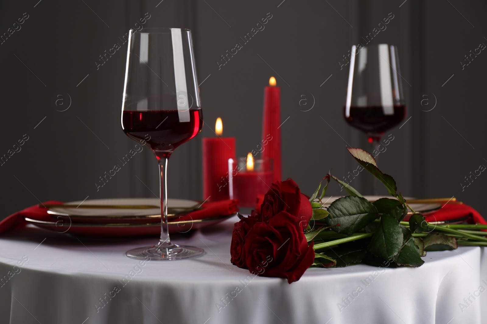 Photo of Place setting with roses and candles on white table. Romantic dinner