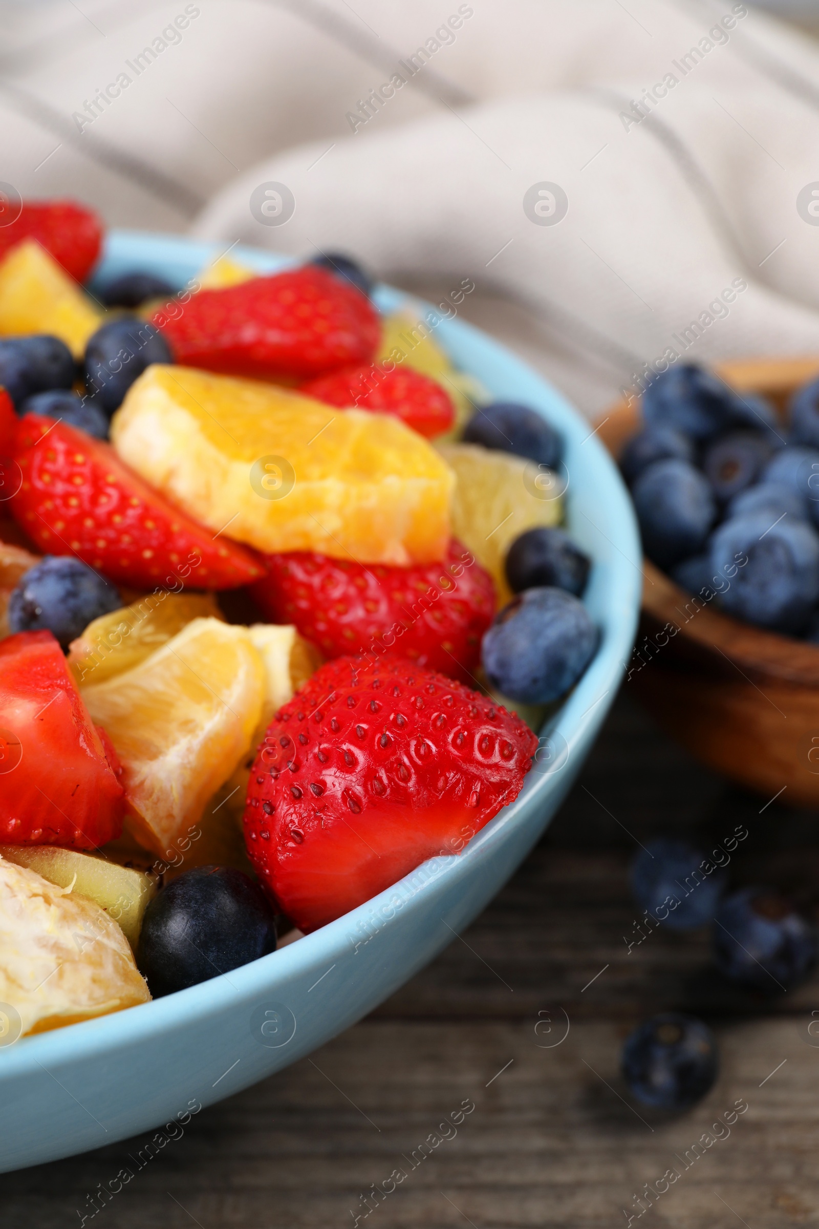 Photo of Delicious fresh fruit salad in bowl on wooden table, closeup