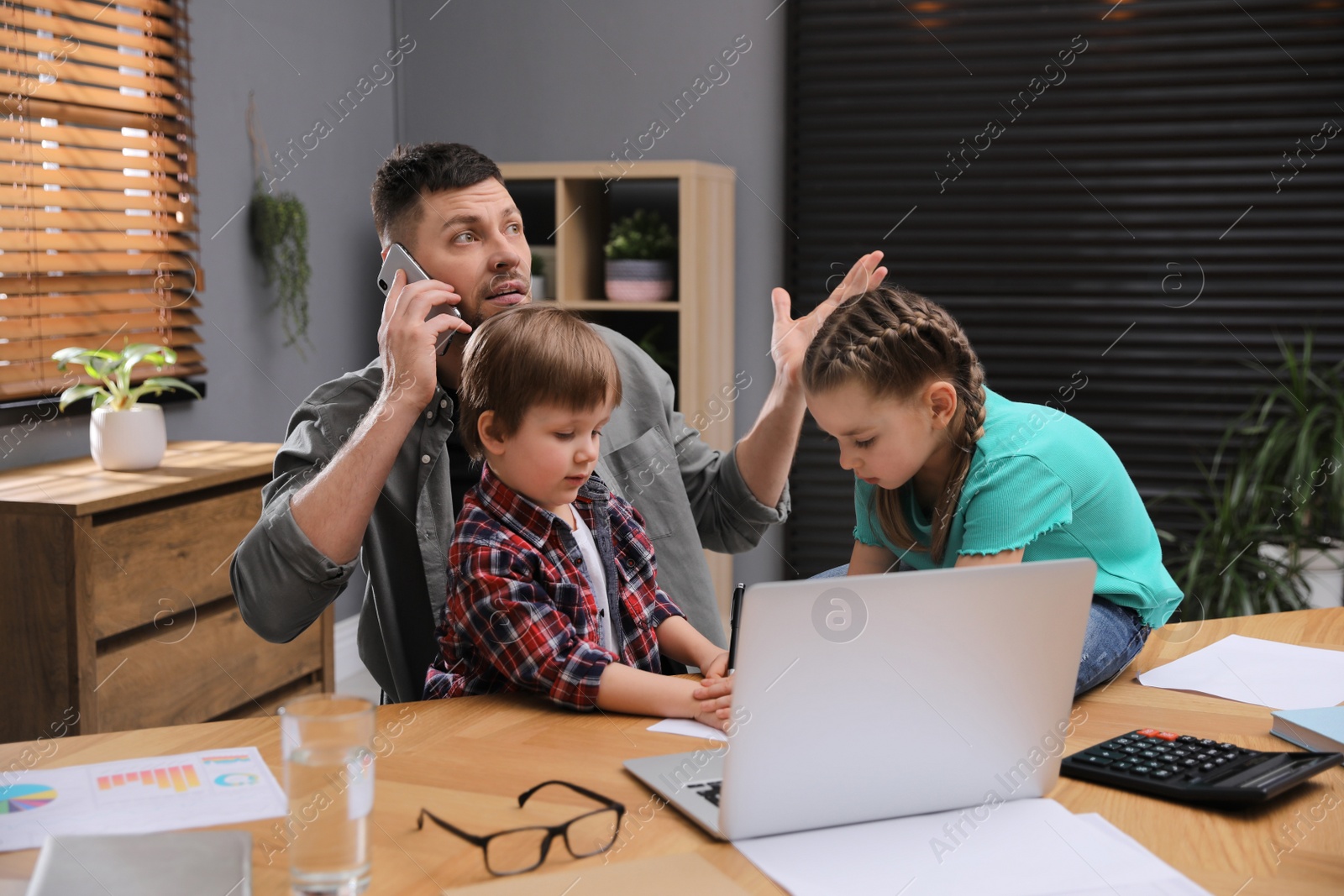 Photo of Overwhelmed man combining parenting and work at home