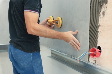 Worker using suction plate for tile installation indoors, closeup