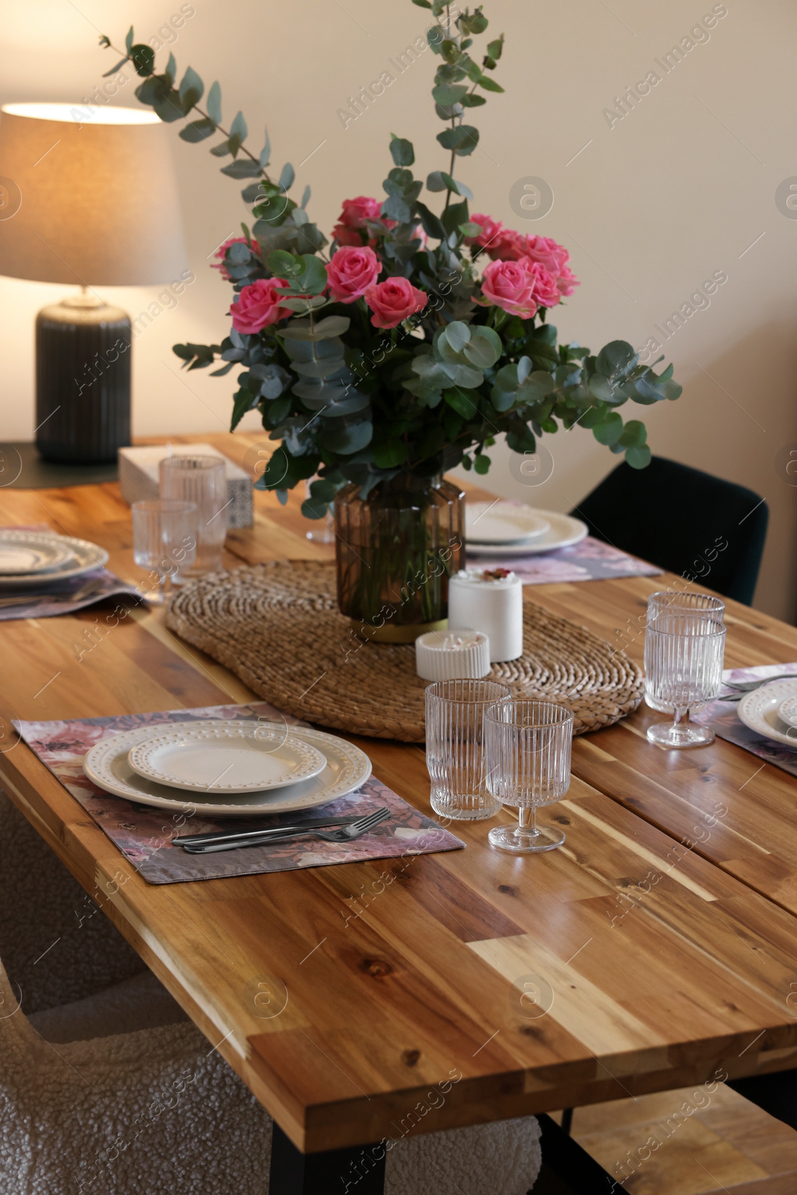 Photo of Beautiful table setting with bouquet and candles indoors. Roses and eucalyptus branches in vase