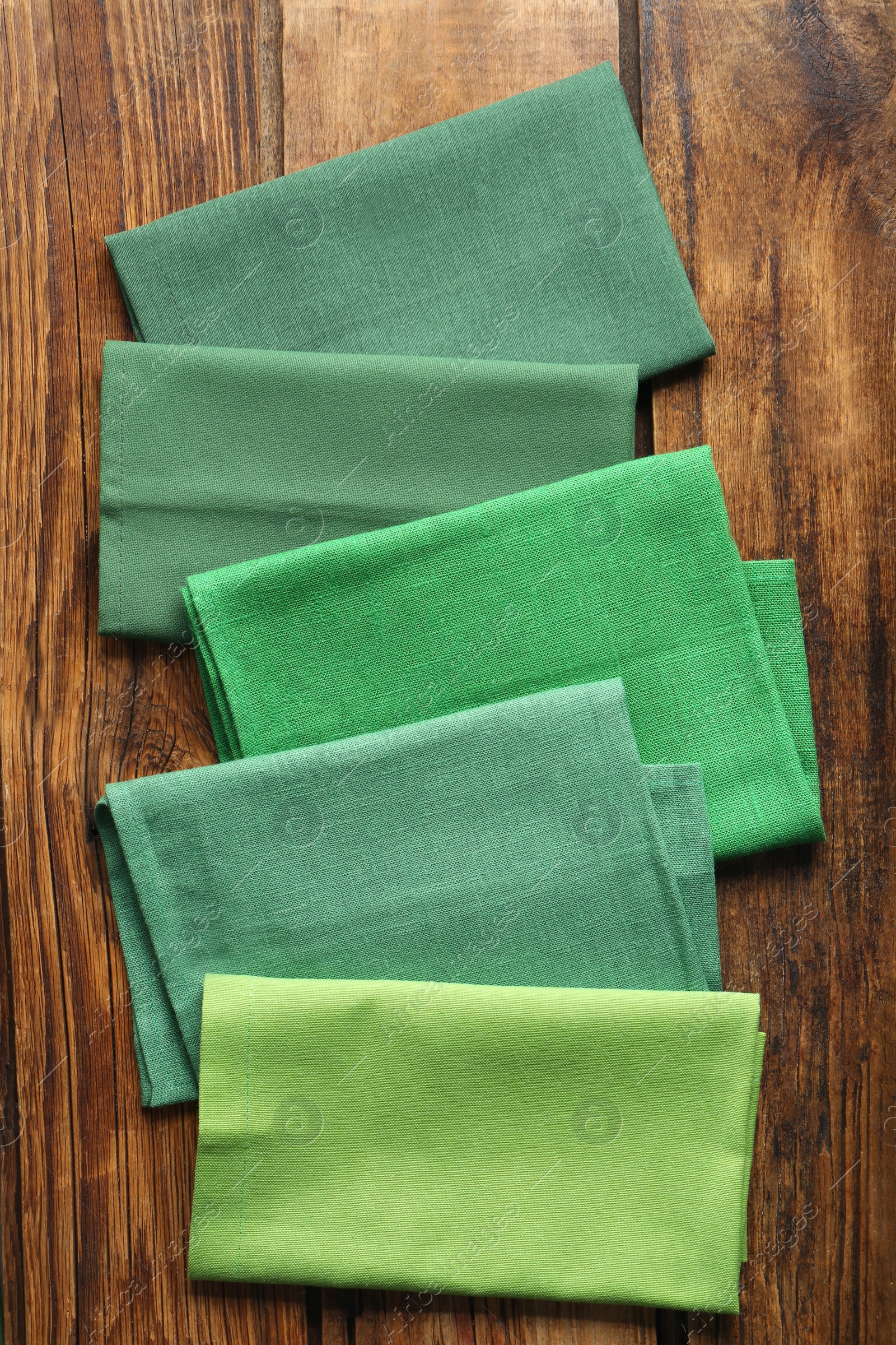 Photo of Different kitchen napkins on wooden table, flat lay