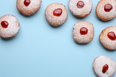 Hanukkah donuts with jelly and powdered sugar on light blue background, flat lay. Space for text