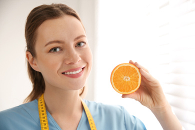 Photo of Nutritionist with orange near window in office