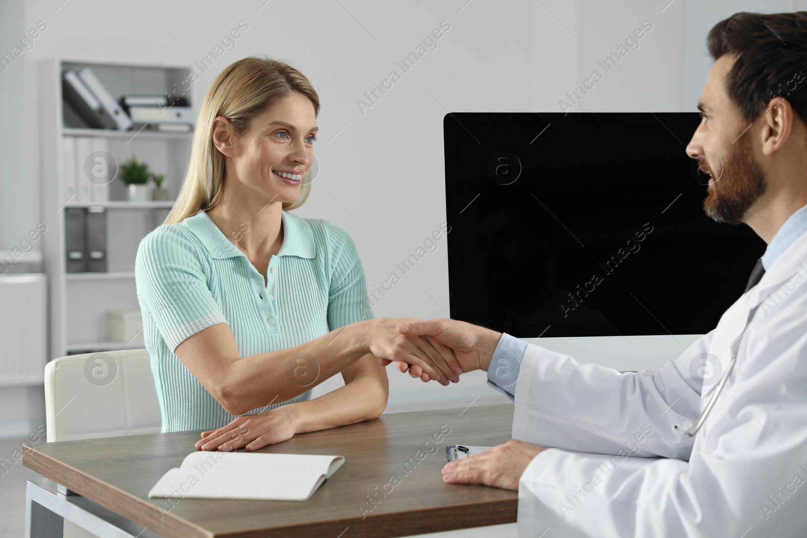 Photo of Doctor shaking hands with happy patient in hospital